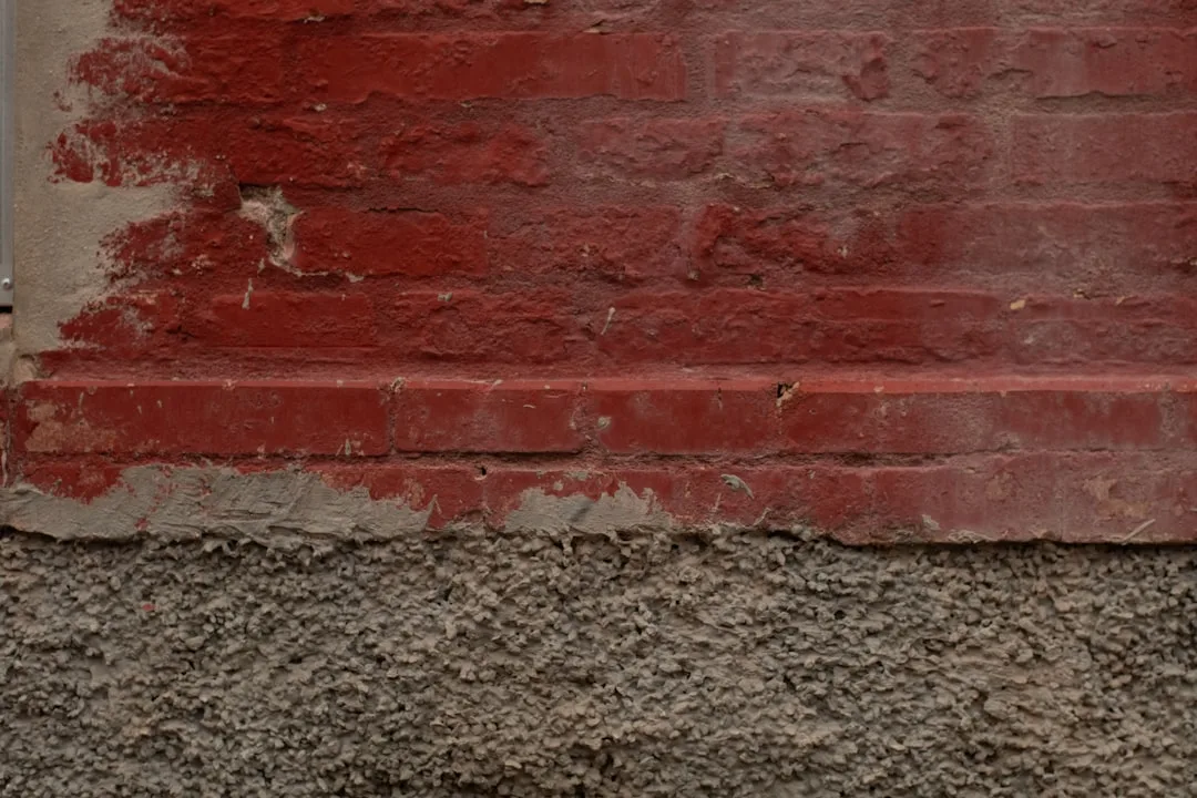 Red brick wall with rough concrete base