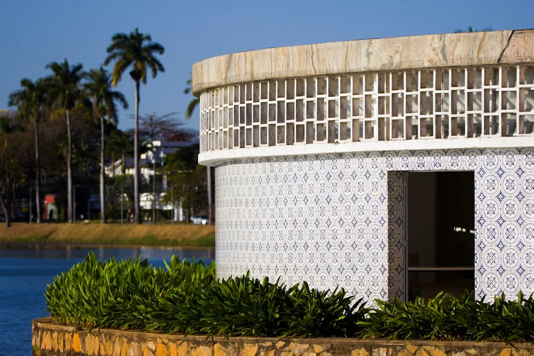 Curved building with patterned tiles by a lake