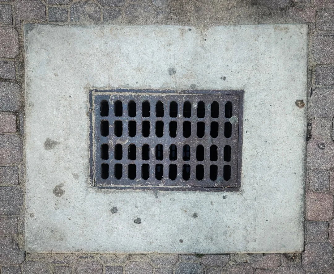 A grate on the side of a brick wall