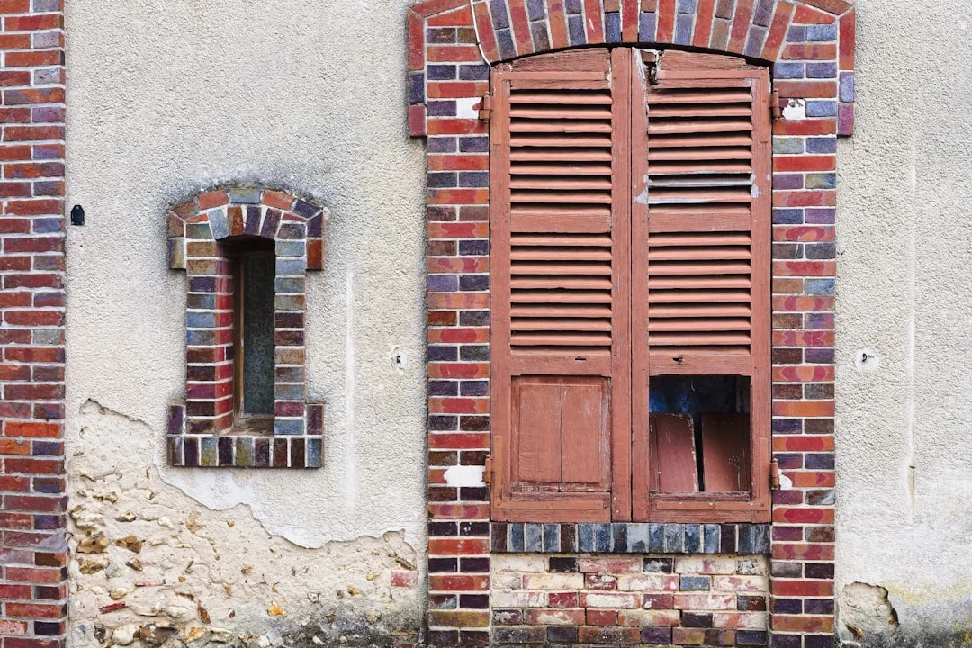 a brick building with two windows and a cat sitting in the window