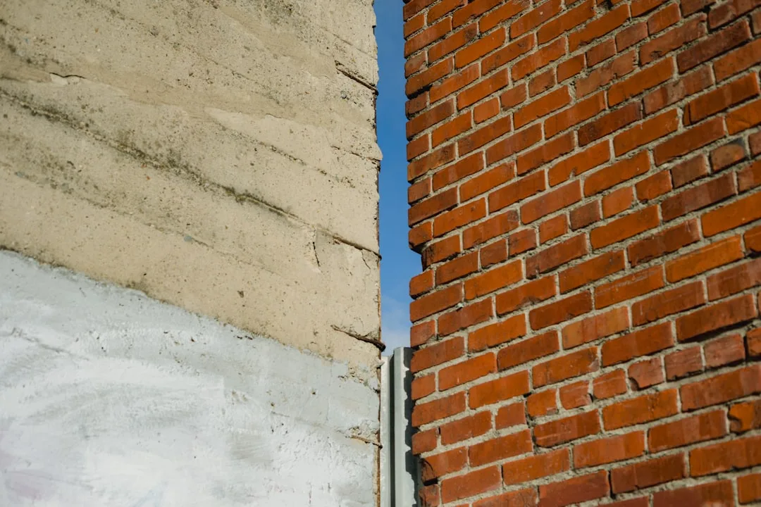 Rough concrete wall next to weathered red brick wall